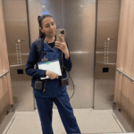 Nurse Darleene taking an elevator mirror selfie in blue scrubs, carrying the compact charger featured in our Anker Nano 10K review.