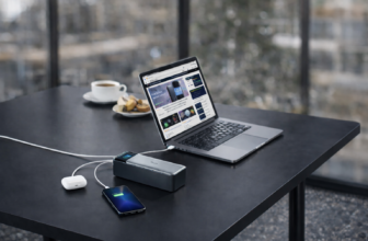 A close-up of an Anker 737 (PowerCore 24K) charging a laptop and smartphone on a table at an airport lounge, showcasing its 140W fast charging and smart digital display. 💻📱