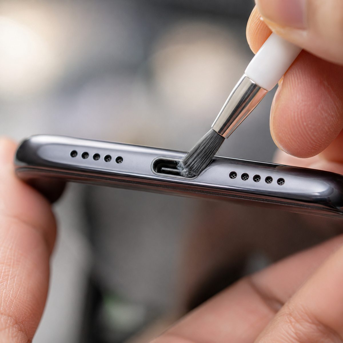 Cleaning lint out of a phone USB-C charging port with a small soft brush